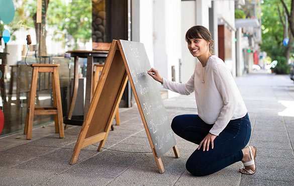 Business woman with A-frame sign out front.