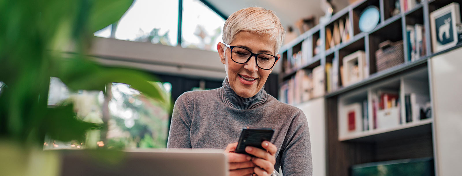 Mature woman at home looking at mobile phone.