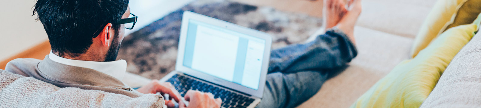 Man using laptop on couch at home.